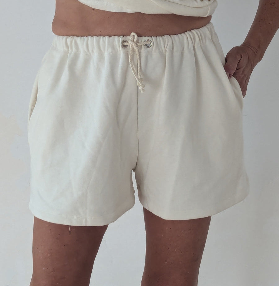 Person wearing beige shorts on a plain background