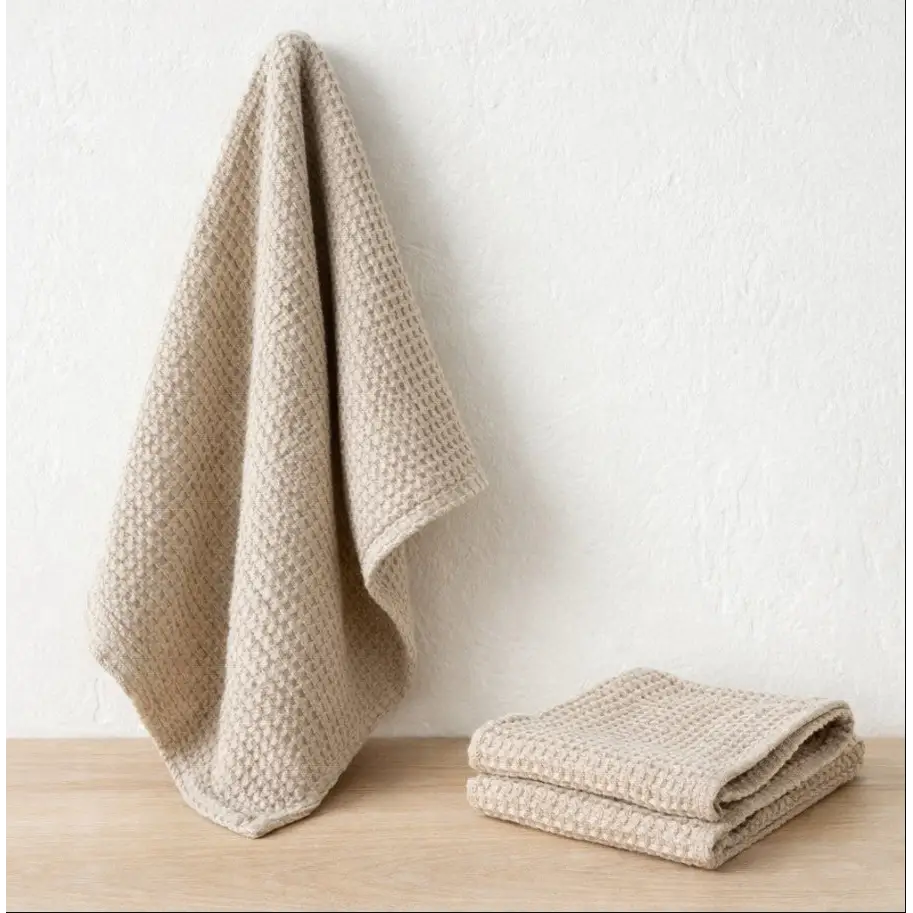 Beige textured towels on a wooden surface with a white background designed by Hemp Horizon
