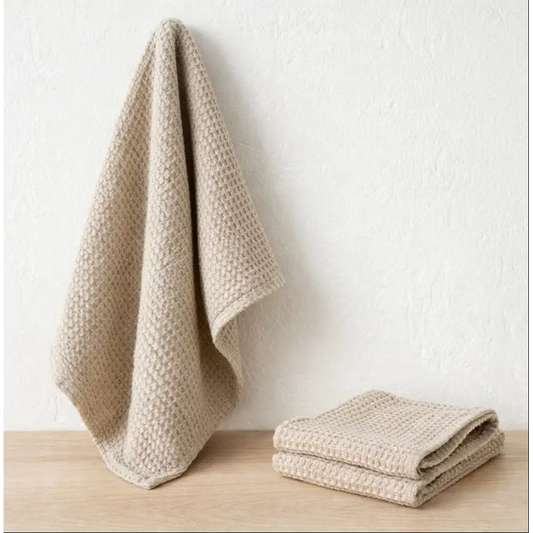 Beige textured towels on a wooden surface with a white background designed by Hemp Horizon