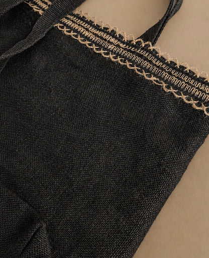 Close-up of a black hemp canvas woven fabric tote bag with a decorative beige jute braided trim along the top edge. Hemp Hoizon