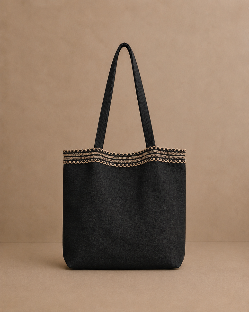 A black hemp canvas tote bag with double shoulder straps and a decorative embroidered border near the top, set against a solid beige background. Hemp Horizon