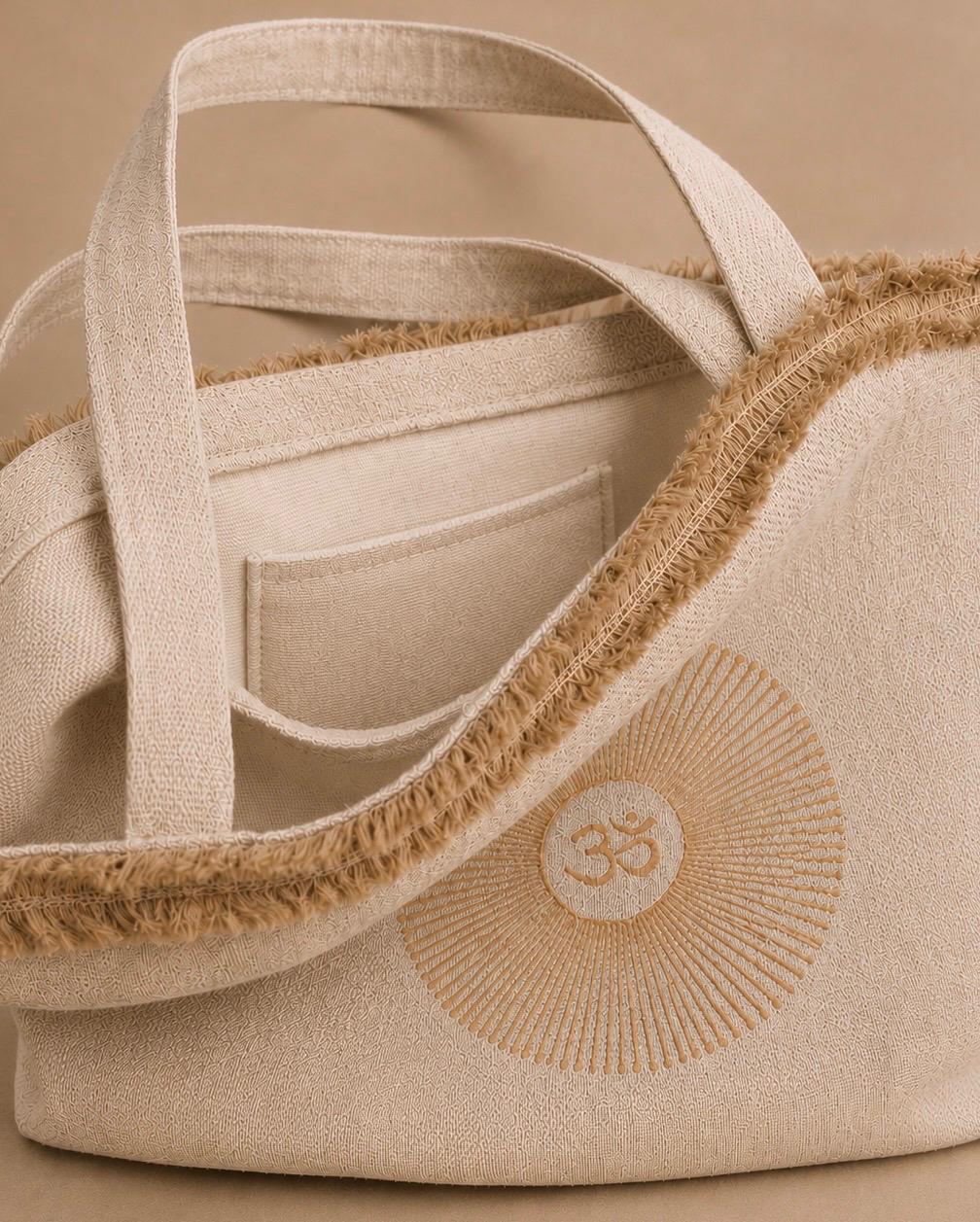 Close-up of a beige hemp canvas tote bag with a natural jute trim, a cream internal pocket, and a block printed circular OM motif on the front - Hemp Horion