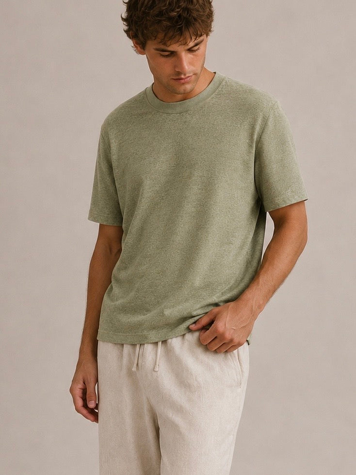 A man wearing a short-sleeve Pure Hemp knit t-shirt in Olive green, paired with light beige drawstring pants, standing against a neutral beige studio background. Hemp Horizon