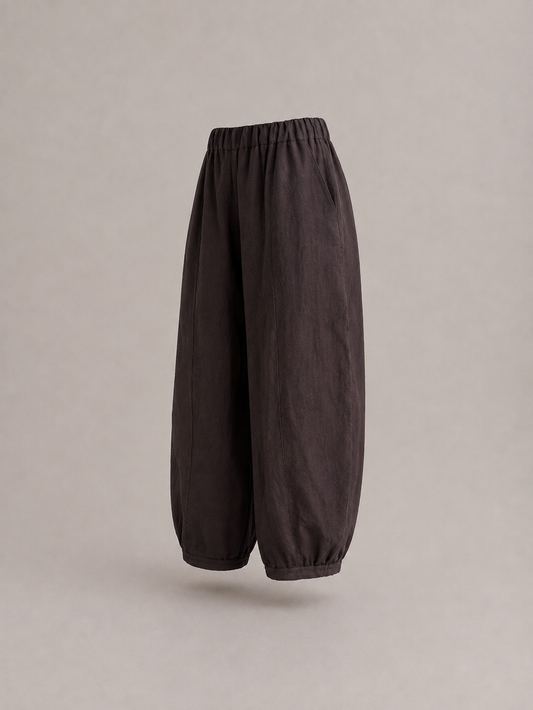 Dark brown baggy pants with an elastic waistband and gathered cuffs, shown floating against a neutral gray background. emp Horizon