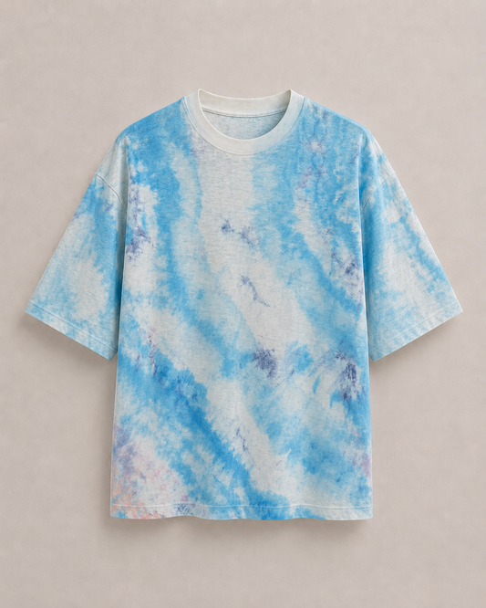 A short-sleeve t-shirt with a pale blue and navy blue on white ice-dye pattern, laid flat against a neutral beige background. Hemp Horizon