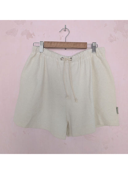 Beige shorts on a hanger against a pink background