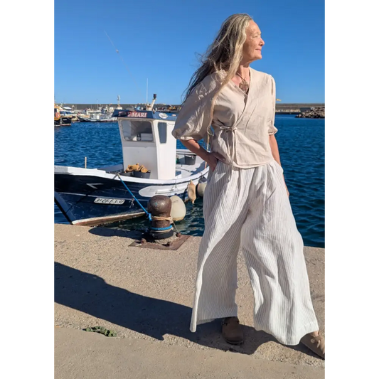 Woman in a light outfit standing by a dock with boats in the background - Hemp Horizon