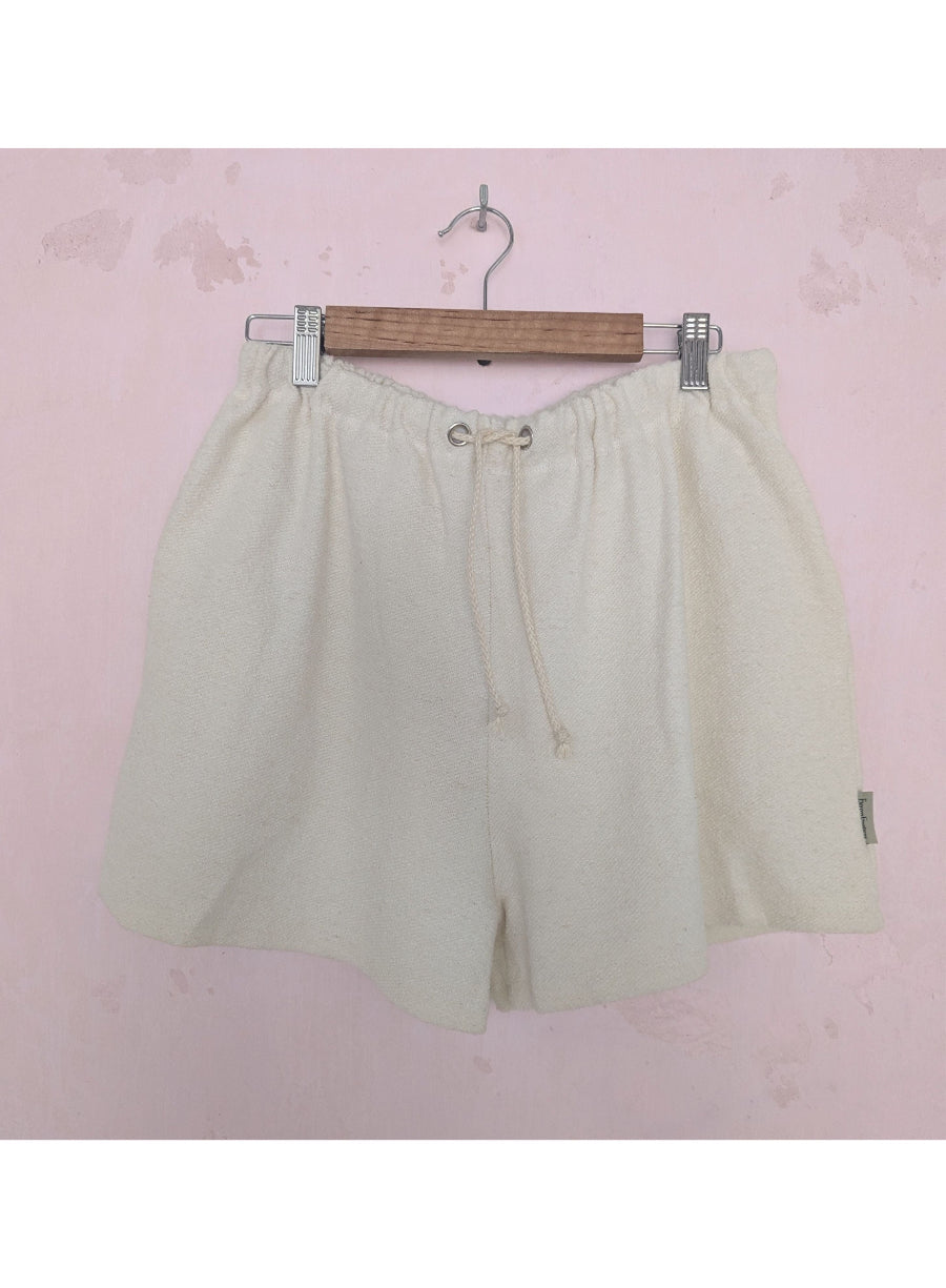 Beige shorts on a hanger against a pink background