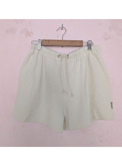 Beige shorts on a hanger against a pink background