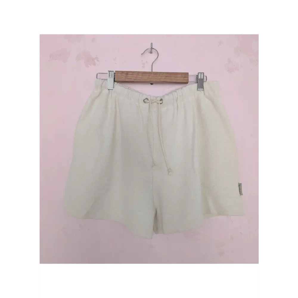Beige shorts on a hanger against a pink background